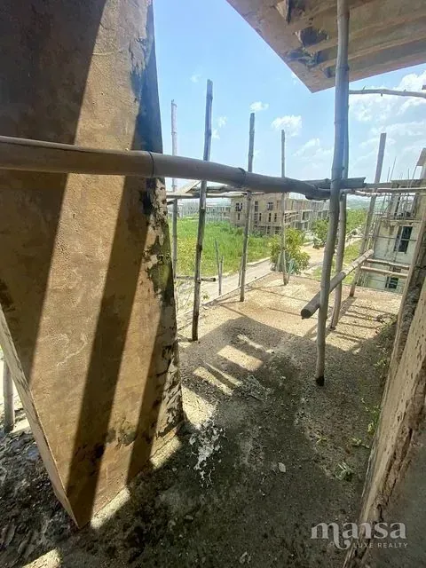 An unfinished balcony with scaffolding, overlooking grassland and neighbouring builds