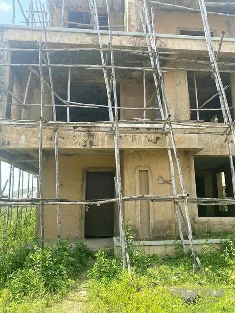 A dark front door in the plastered facade, behind bamboo scaffolding