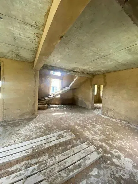 An unfinished ground-floor room with plastered walls