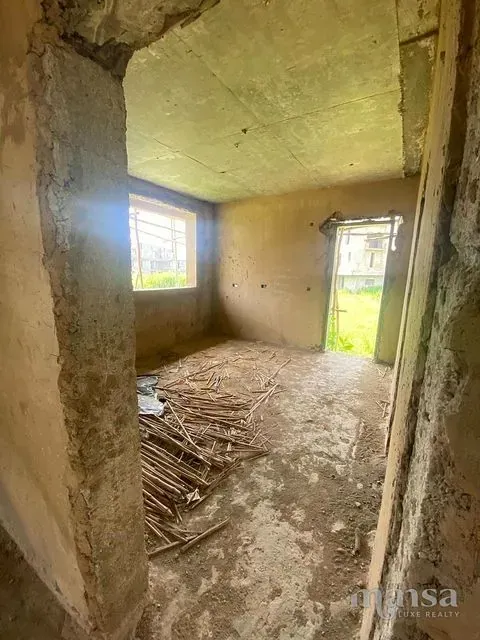 An unfinished room with window openings on two walls
