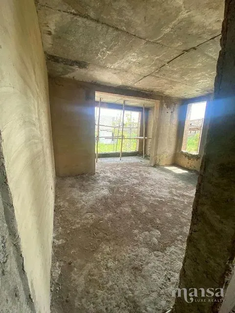 An unfinished room with wide window openings to the grounds