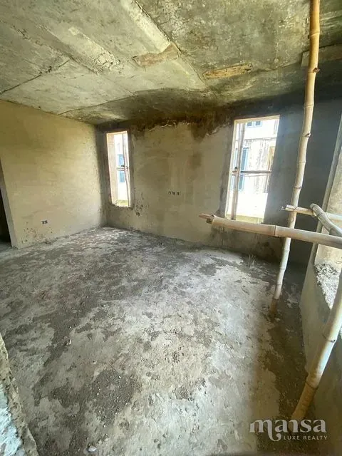 An unfinished plastered room with one window opening