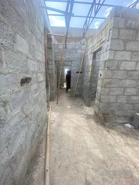 A corridor between bare block walls leading to further rooms
