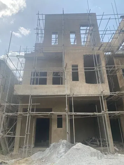 The front of a three-storey 5-bedroom detached duplex carcass in Katampe Extension, Abuja, in bare blockwork with scaffolding up