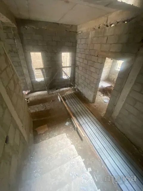 An unfinished room with bare block walls and two window openings