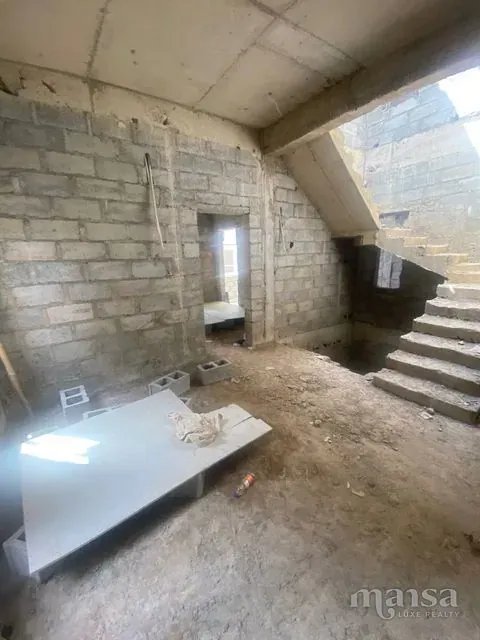 An unfinished room beside the concrete staircase