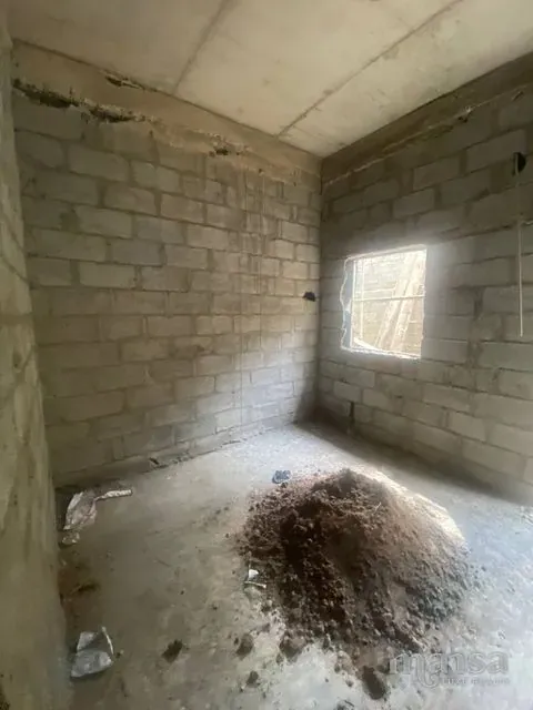 An unfinished room with bare block walls and a window opening