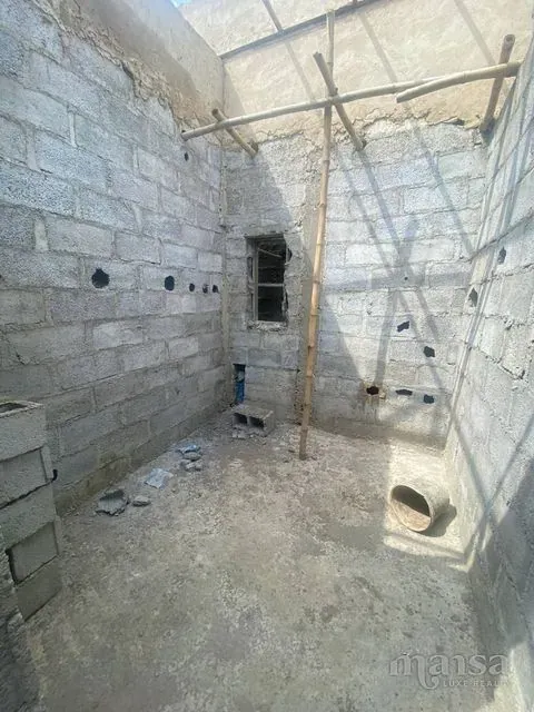 An unfinished room with block walls and a single window opening