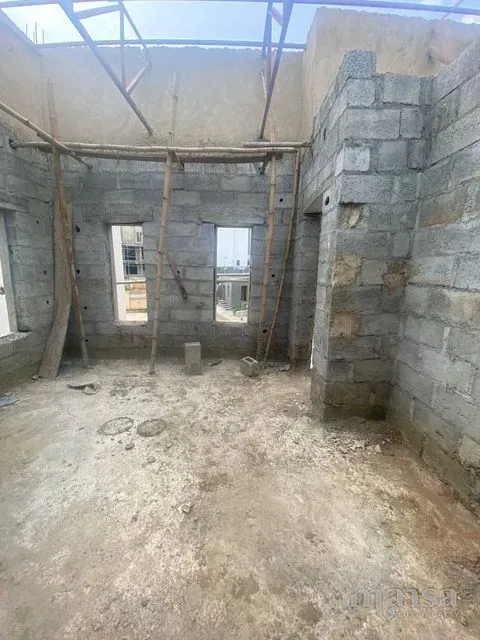 An unfinished room with two windows and the roof trusses above