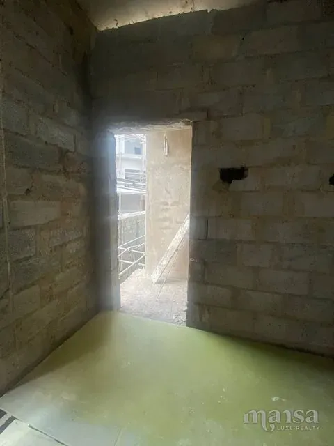 An unfinished room with a doorway through to another room