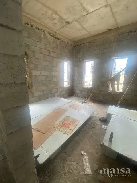 An unfinished room with three window openings along one wall