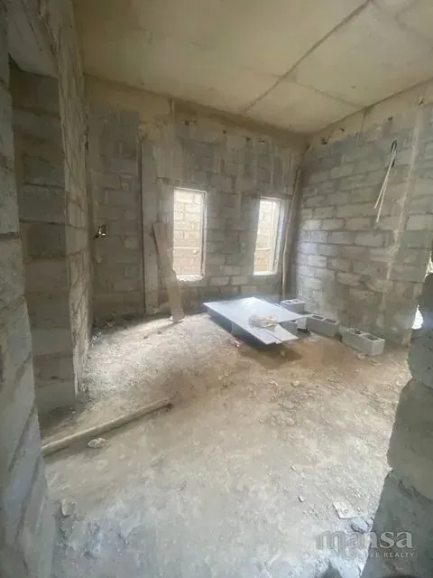 An unfinished room with two window openings