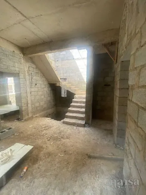 A cast concrete staircase rising between bare block walls