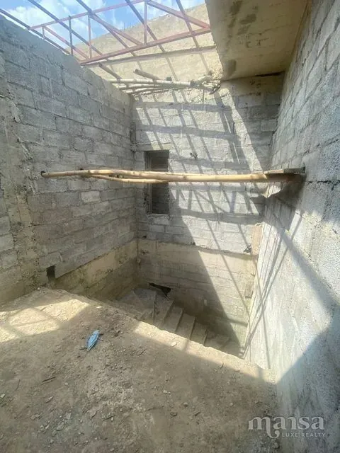 An upper-floor room open to the sky beneath steel roof trusses