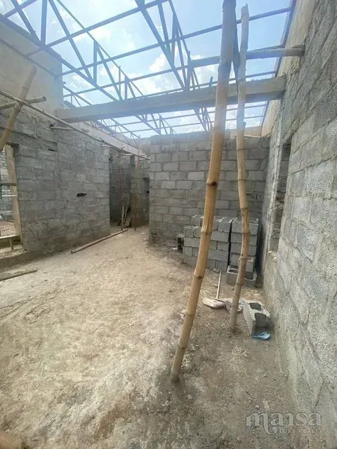 A large top-floor space with steel roof trusses overhead and bamboo props