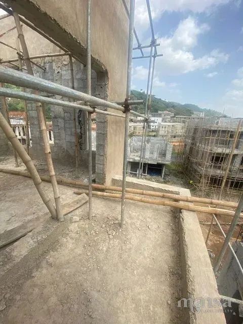 View from an upper floor through scaffolding towards green hills