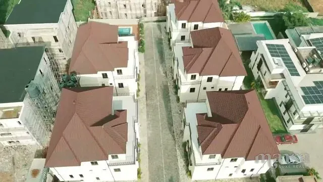 Top-down aerial view of a mini estate of detached duplexes with red roofs along a paved road