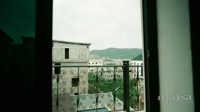 View through a balcony door to ornate iron railings and the neighbourhood beyond