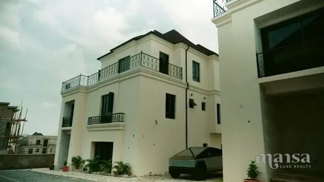 A white three-storey detached duplex with balconies and wrought-iron railings in a mini estate in Katampe Extension, Abuja