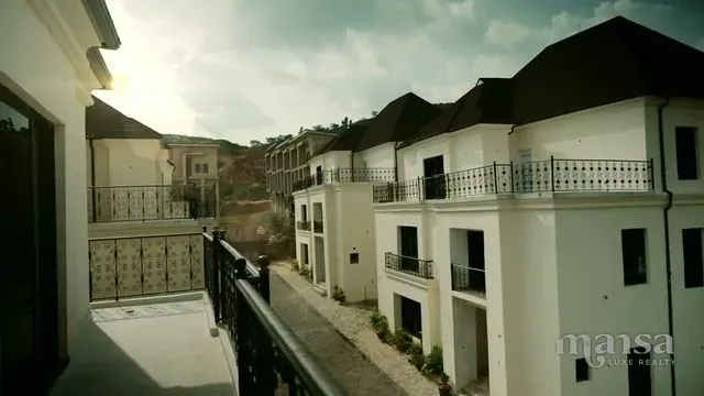 A row of white detached duplexes with ornate balconies, seen from an upper-floor balcony in Katampe Extension