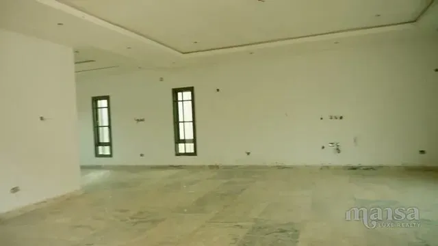 A large empty room with white walls, tall dark-framed windows and a recessed ceiling