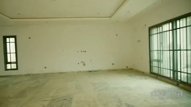 A large empty room with floor-to-ceiling glass doors along one wall