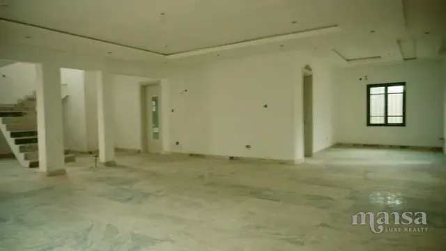 An open-plan interior with columns and a staircase in the background