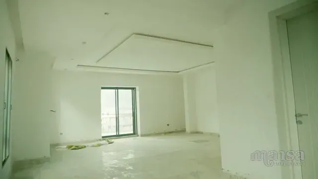 An empty white room with a window and sunlight falling across the floor