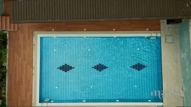 Top-down view of a rectangular swimming pool with blue tiles and a diamond pattern on the floor