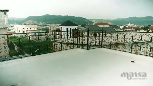 A white rooftop terrace with an iron railing, overlooking neighbouring duplexes