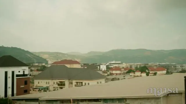 View from the top floor over rooftops towards green hills