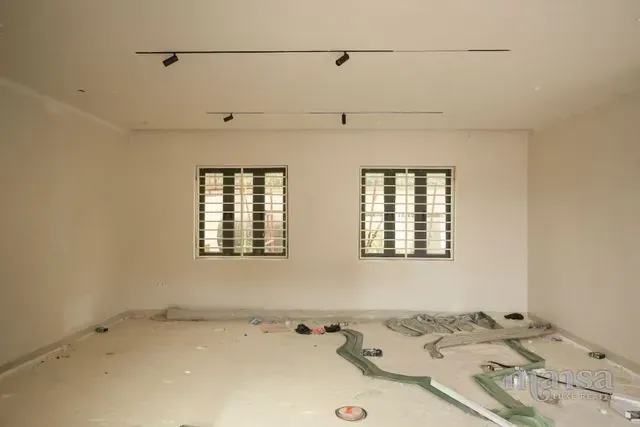An interior room of the Katampe Extension house during finishing, with track lighting fitted and the floor not yet laid