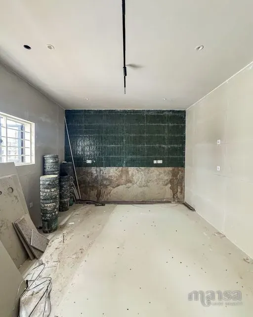 The kitchen's dark green feature wall part-way through tiling in the Katampe Extension house