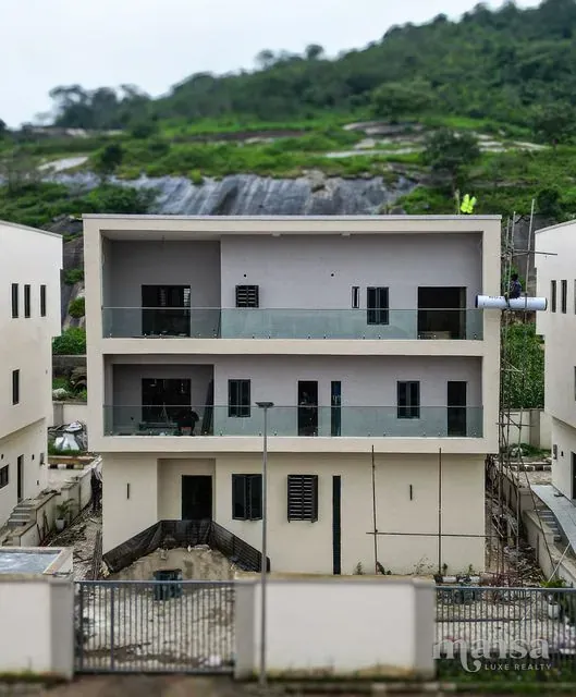 The Katampe Extension house seen head-on from the street during the build, with the Katampe rock outcrop rising behind it