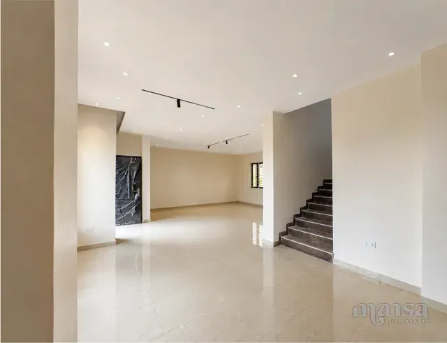 A reception area and staircase with a dark marble feature wall in the Katampe Extension house, before completion